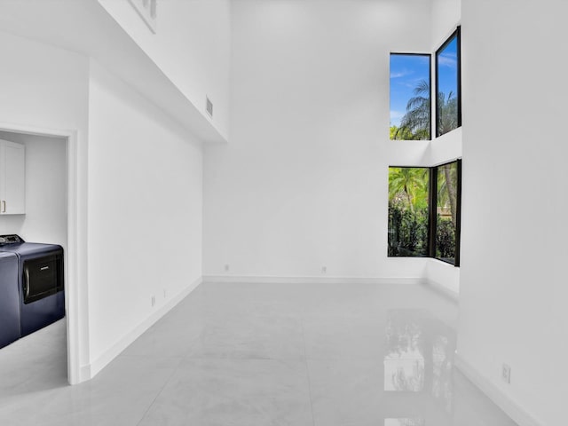 13759 Parc Dr, Palm Beach Gardens, FL 33410 - empty room featuring washer / clothes dryer, a high ceiling, baseboards, and light tile patterned floors