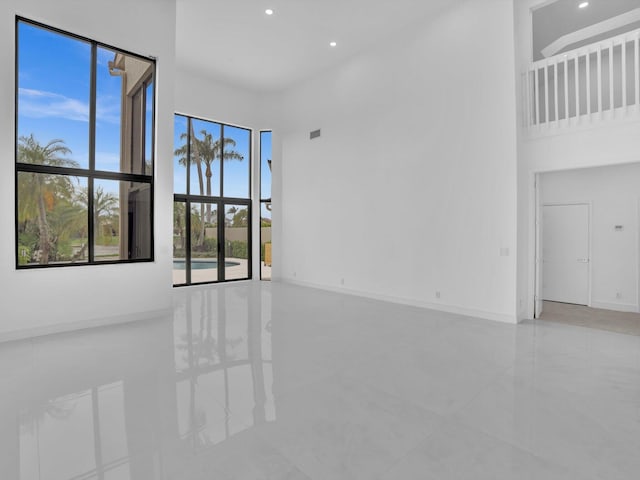 spare room featuring a high ceiling, recessed lighting, baseboards, and tile patterned floors