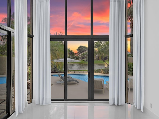 doorway featuring tile patterned flooring, a water view, and floor to ceiling windows