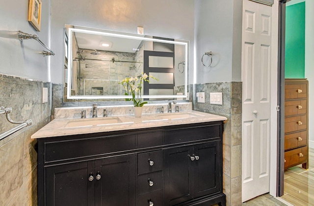 2430 NW 14th St, Delray Beach, FL 33445 - bathroom featuring tile walls, double vanity, a shower stall, and a wainscoted wall