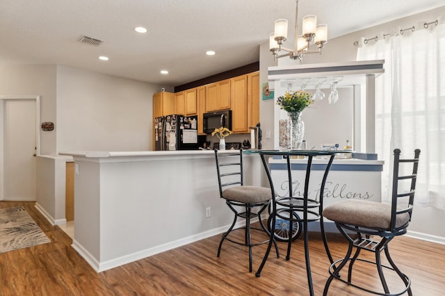 kitchen with visible vents, light wood finished floors, recessed lighting, black appliances, and light brown cabinetry