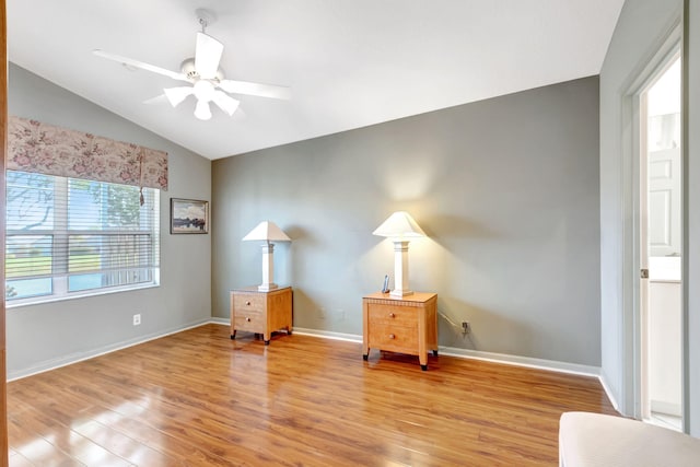 interior space featuring a ceiling fan, light wood-style flooring, baseboards, and vaulted ceiling