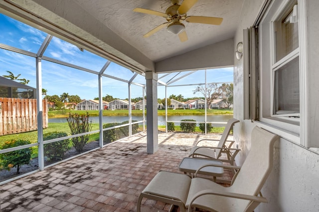 sunroom / solarium featuring a ceiling fan, plenty of natural light, and a water view