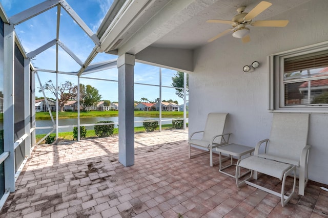 sunroom featuring a residential view, a water view, and ceiling fan