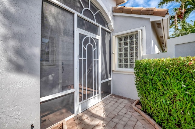 doorway to property featuring a tile roof and stucco siding