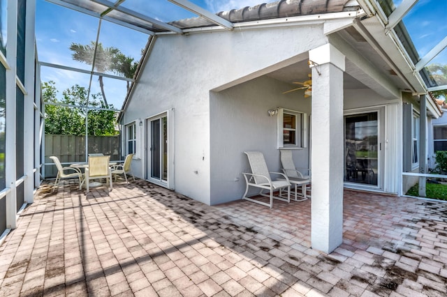 view of patio / terrace with outdoor dining area, a lanai, fence, and ceiling fan