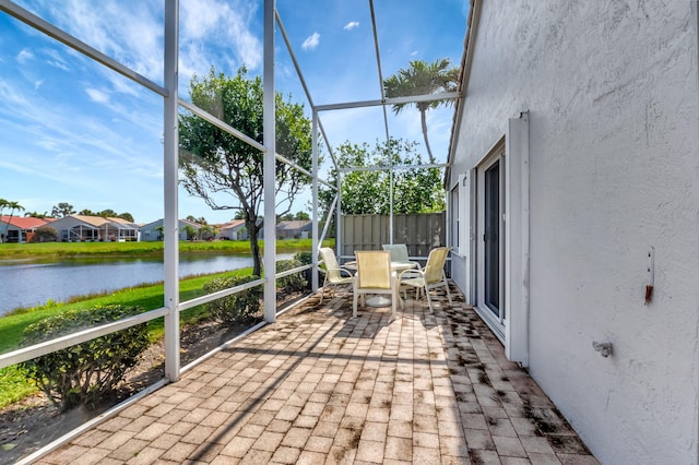 unfurnished sunroom with a water view and outdoor dining space