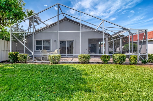rear view of property featuring stucco siding, a lanai, a patio, and a yard