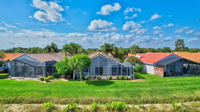 rear view of house featuring a tile roof, a lanai, and a yard