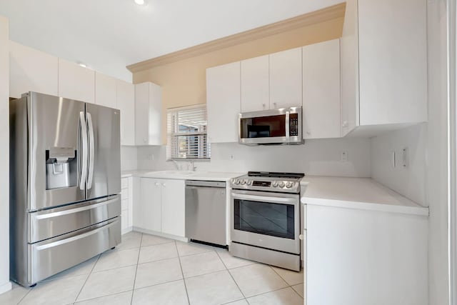 kitchen with light countertops, crown molding, a sink, light tile patterned flooring, and appliances with stainless steel finishes