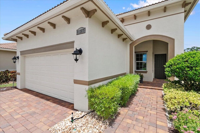 11227 SW Visconti Way, Port Saint Lucie, FL 34986 - doorway to property featuring an attached garage, a tiled roof, and stucco siding