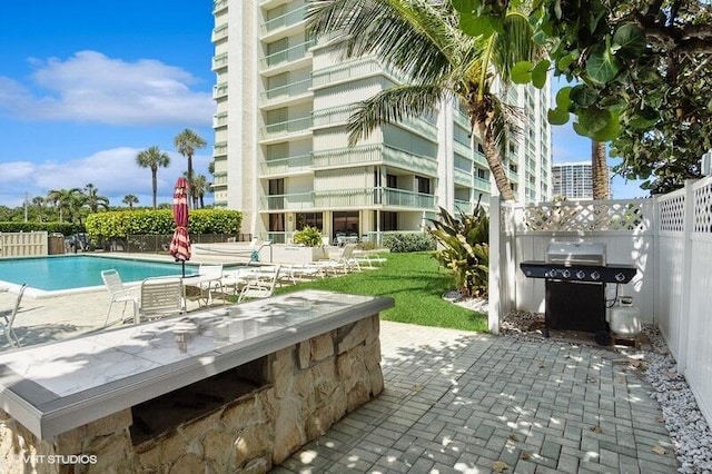 exterior space featuring grilling area, fence, and a community pool