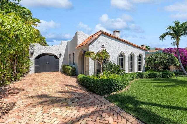 235 Nottingham Blvd, West Palm Beach, FL 33405 - view of front facade with a gate, decorative driveway, a front yard, stucco siding, and a tiled roof