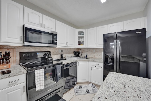 9441 W Mcnab Rd Unit 111, Tamarac, FL 33321 - kitchen with black appliances, light stone countertops, glass insert cabinets, white cabinetry, and light tile patterned floors