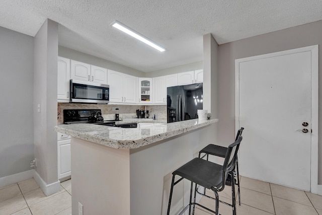 9441 W Mcnab Rd Unit 111, Tamarac, FL 33321 - kitchen featuring black appliances, light tile patterned flooring, a breakfast bar, glass insert cabinets, and a textured ceiling