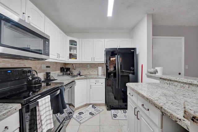 9441 W Mcnab Rd Unit 111, Tamarac, FL 33321 - kitchen featuring black appliances, a sink, light tile patterned flooring, tasteful backsplash, and light stone counters