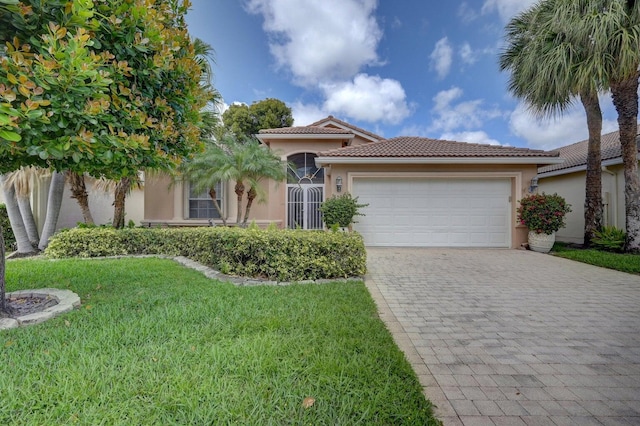 view of front facade with decorative driveway, an attached garage, a tile roof, a front lawn, and stucco siding