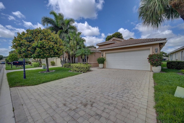 view of front of property with a tiled roof, decorative driveway, a garage, a front lawn, and stucco siding