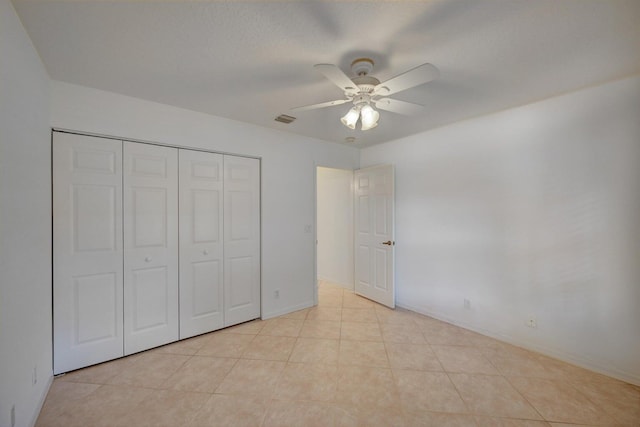 unfurnished bedroom featuring light tile patterned floors, baseboards, visible vents, a ceiling fan, and a closet