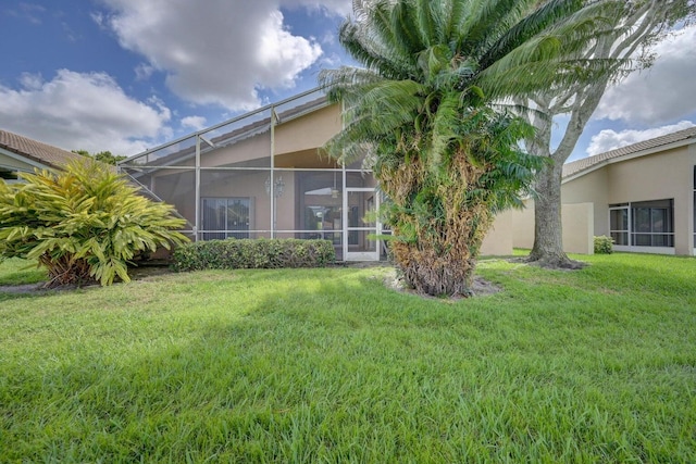 exterior space featuring stucco siding, a lawn, and glass enclosure