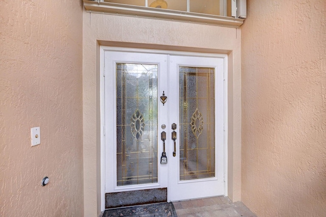 view of exterior entry featuring stucco siding and french doors
