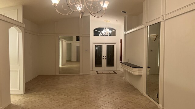 corridor with french doors, light tile patterned floors, high vaulted ceiling, a chandelier, and visible vents