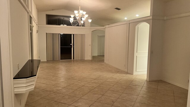 empty room featuring an inviting chandelier, light tile patterned flooring, arched walkways, and vaulted ceiling