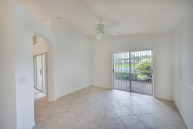 unfurnished room with arched walkways, lofted ceiling, ceiling fan, and light tile patterned floors