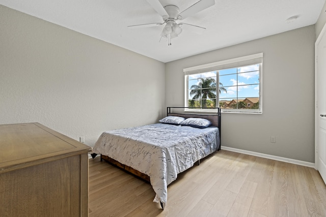 bedroom with light wood finished floors, baseboards, and a ceiling fan
