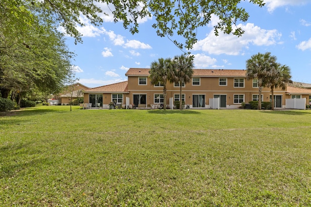 back of property featuring stucco siding and a yard