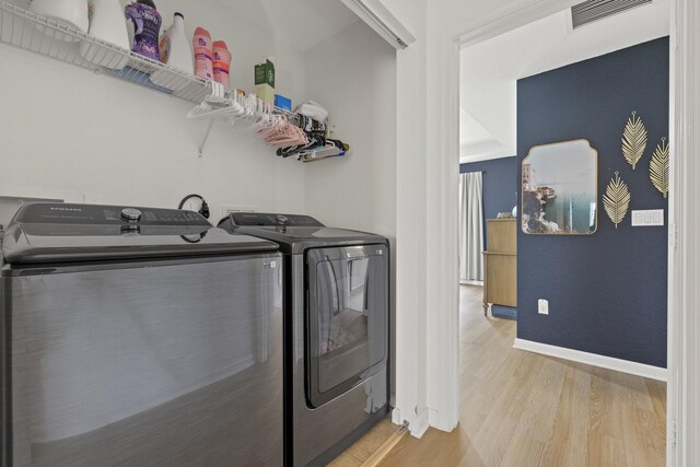 laundry area featuring washing machine and clothes dryer, light wood finished floors, and baseboards