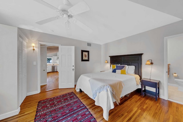 bedroom with ceiling fan, baseboards, wood finished floors, ensuite bathroom, and visible vents