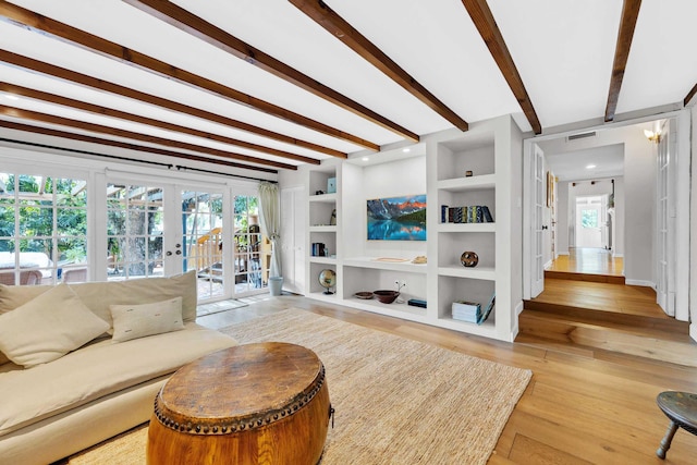 living area featuring light wood finished floors, built in shelves, french doors, beamed ceiling, and visible vents