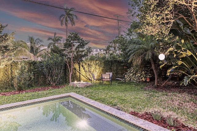 yard at dusk featuring an outdoor pool
