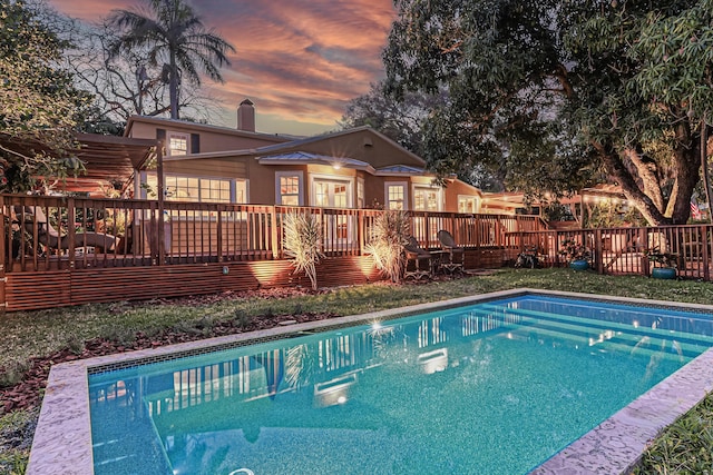 pool at dusk featuring a fenced in pool and a deck