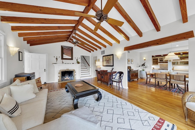 living room with a fireplace with flush hearth, lofted ceiling with beams, a ceiling fan, and wood finished floors