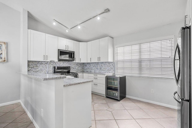 kitchen with stainless steel appliances, tasteful backsplash, vaulted ceiling, and beverage cooler