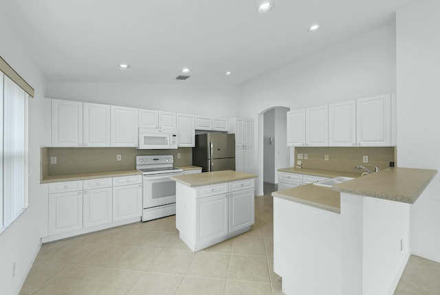 7130 Catania Dr, Boynton Beach, FL 33472 - kitchen with vaulted ceiling, a sink, light tile patterned floors, white appliances, and arched walkways