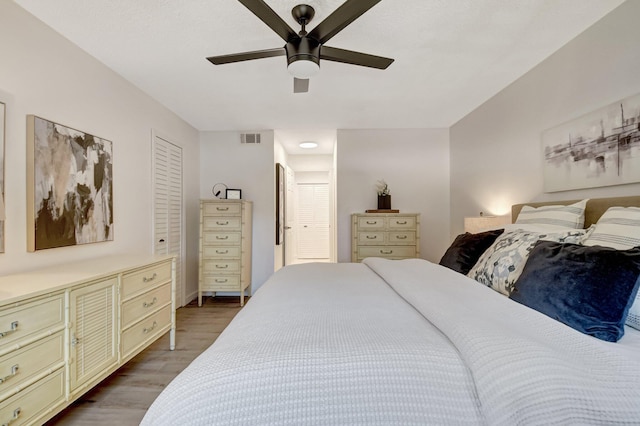 bedroom with a ceiling fan, wood finished floors, and visible vents