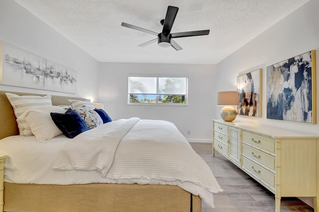 bedroom featuring baseboards, a ceiling fan, wood finished floors, and a textured ceiling