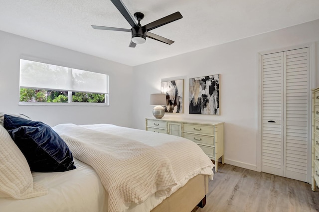 bedroom with light wood finished floors, baseboards, a closet, and ceiling fan