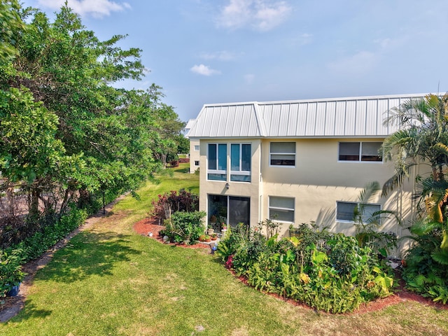 back of property with a lawn and stucco siding