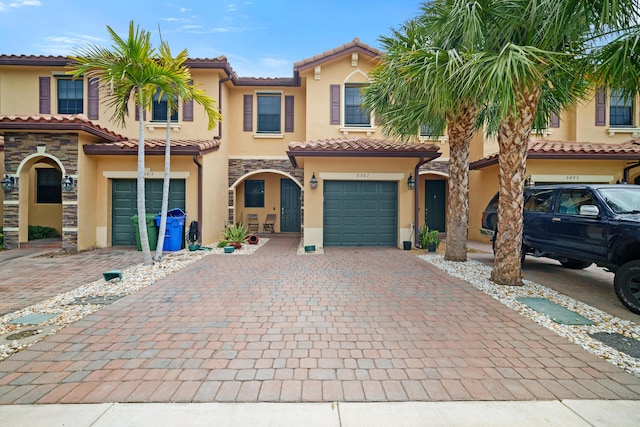 view of front of home featuring stucco siding, stone siding, a tiled roof, and decorative driveway