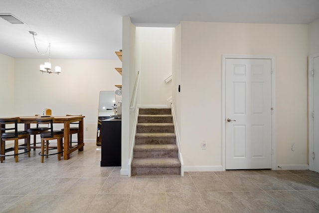 staircase with baseboards, visible vents, an inviting chandelier, and tile patterned floors