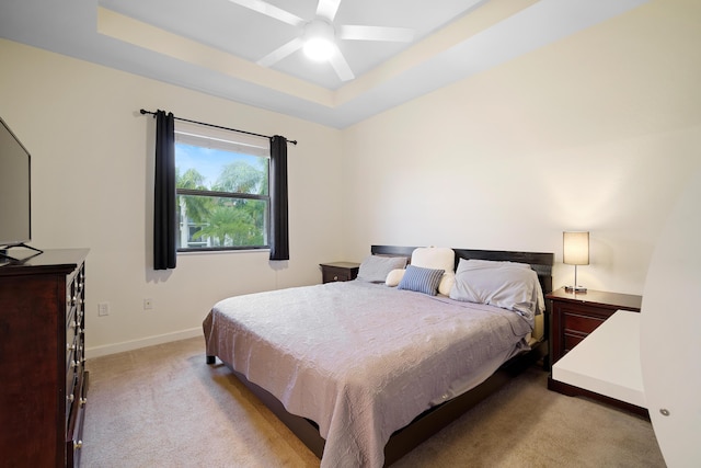 carpeted bedroom featuring a ceiling fan, a raised ceiling, and baseboards