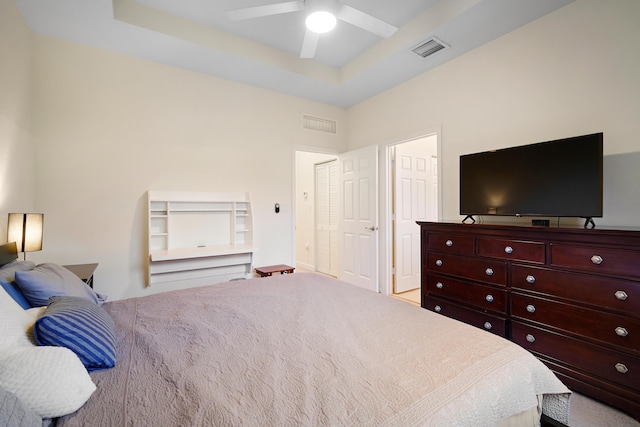 bedroom featuring a tray ceiling, visible vents, and a ceiling fan