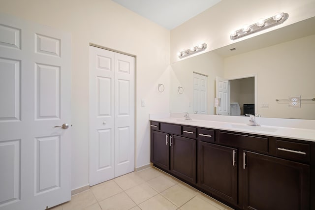 bathroom with double vanity, a closet, tile patterned flooring, and a sink