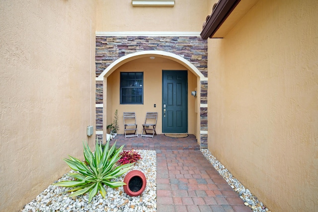 view of exterior entry featuring stucco siding and stone siding