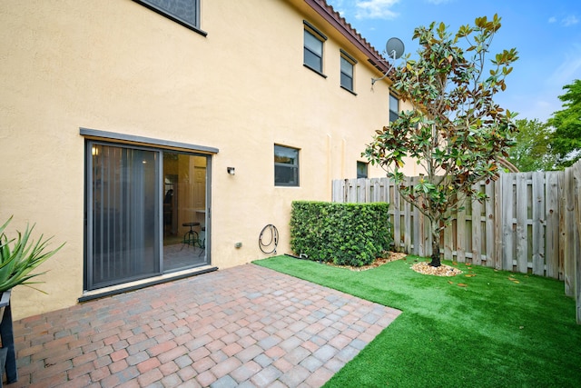 back of property with a lawn, stucco siding, fence, and a patio