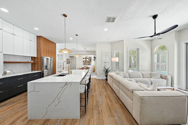 kitchen with a sink, high quality fridge, modern cabinets, open floor plan, and a breakfast bar area